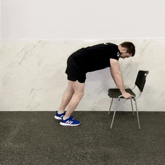 Extensió de cuixa reclinat amb ajuda d'una cadira. Exercici per entrenar glutis a casa o al gimnàs